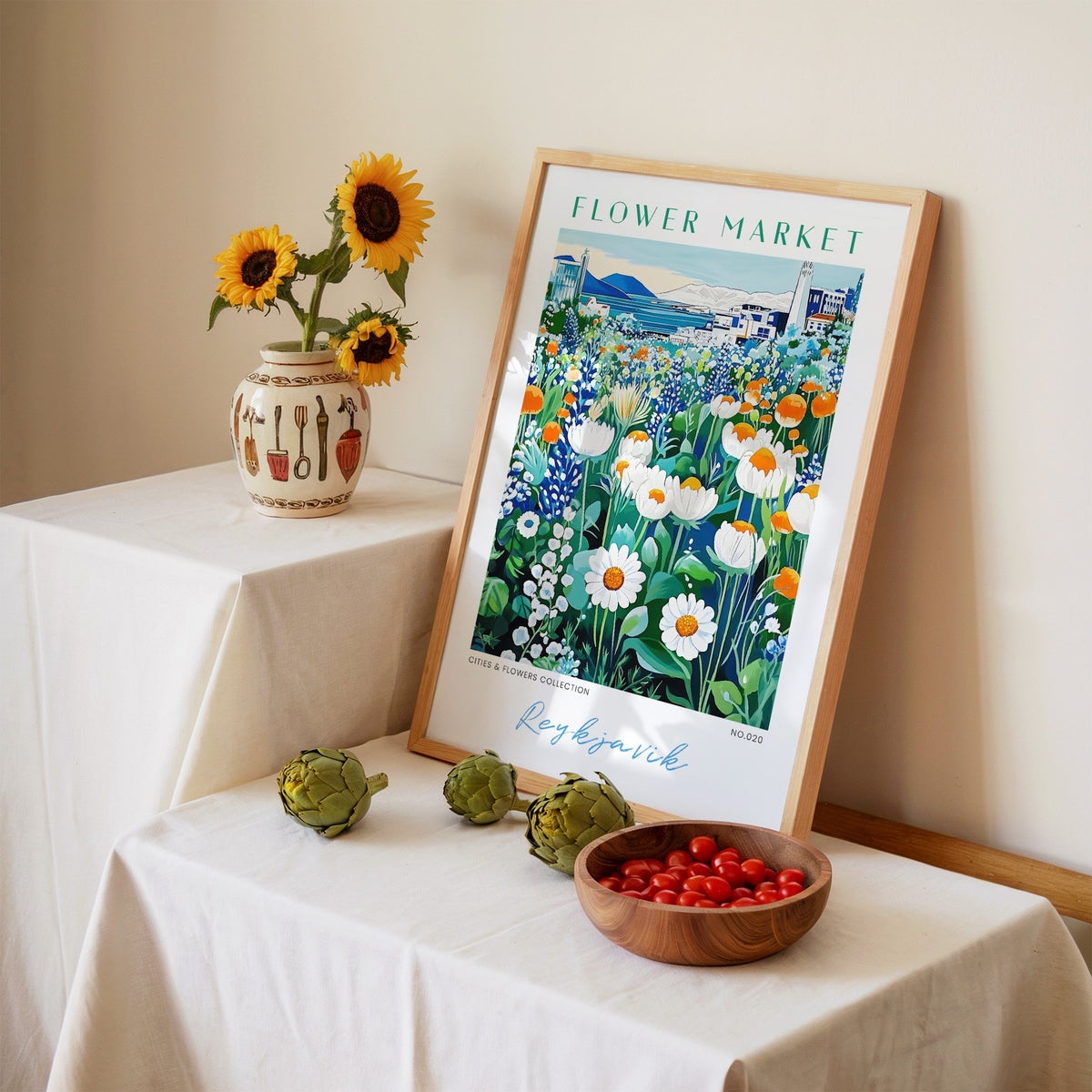 Reykjavik flower market print in an oak frame leaning on a linen-draped table beside a vase of sunflowers