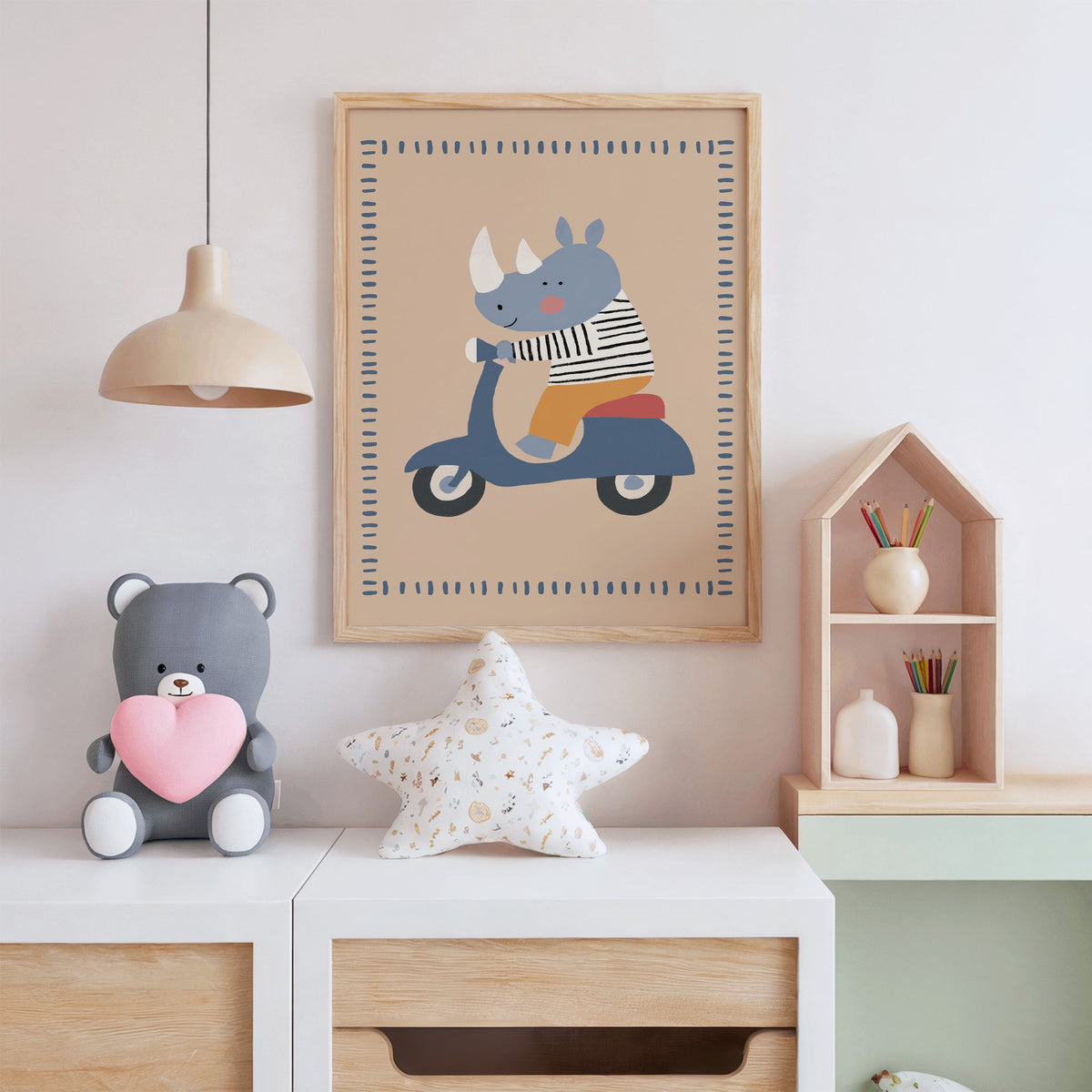 Rhino on a blue scooter nursery print in an oak frame above a white dresser with a star pillow and house shelf