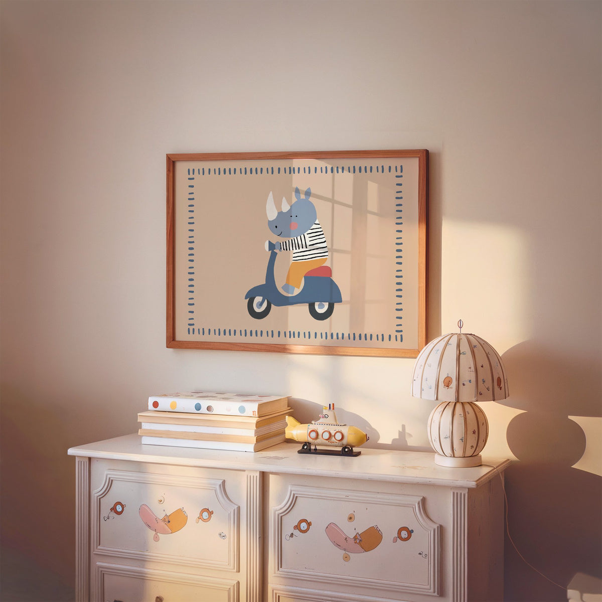 Landscape rhino on a blue scooter nursery print in a cherry wood frame above a painted dresser and lamp