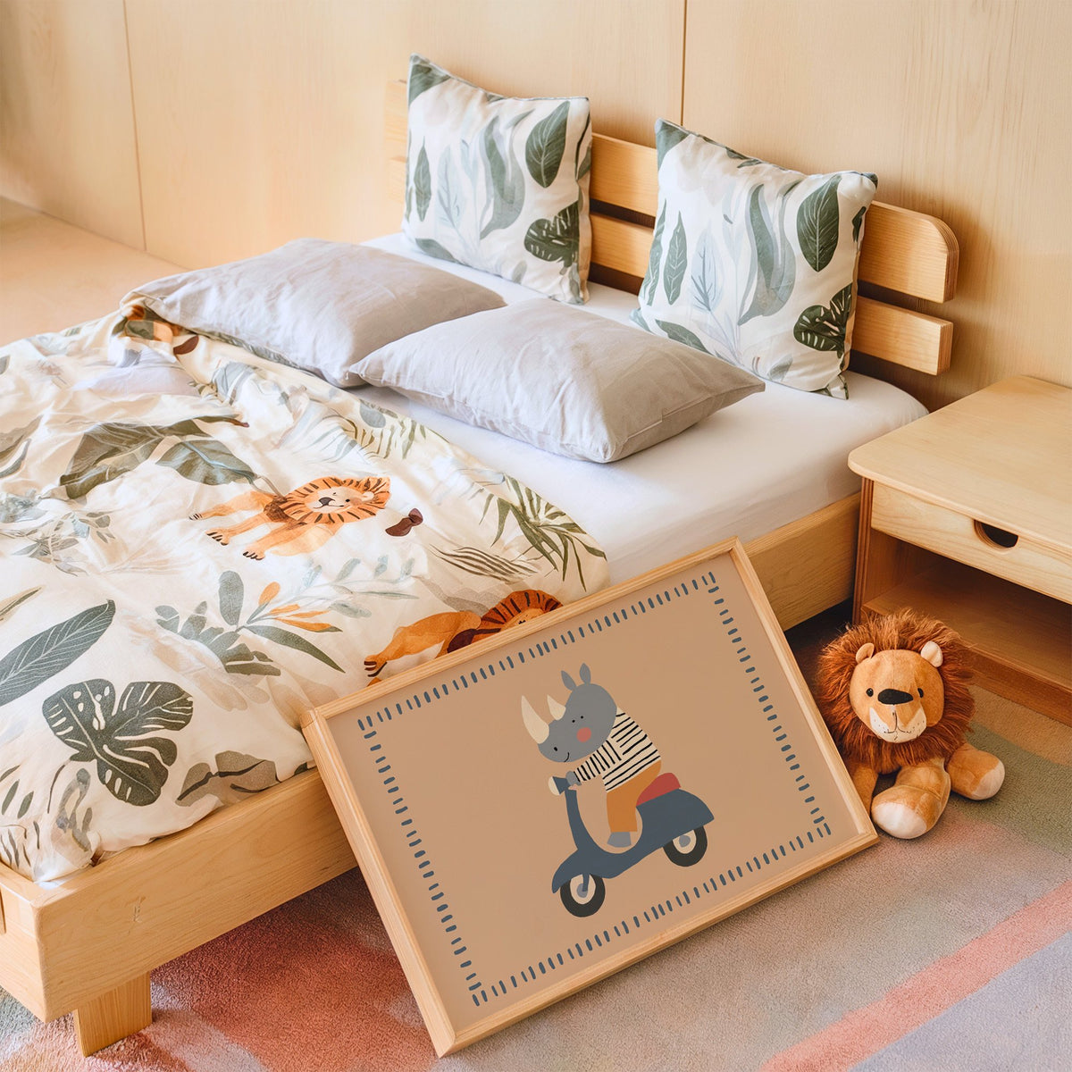 Landscape rhino on a blue scooter nursery print in an oak frame leaning on a kids bed by a lion plush