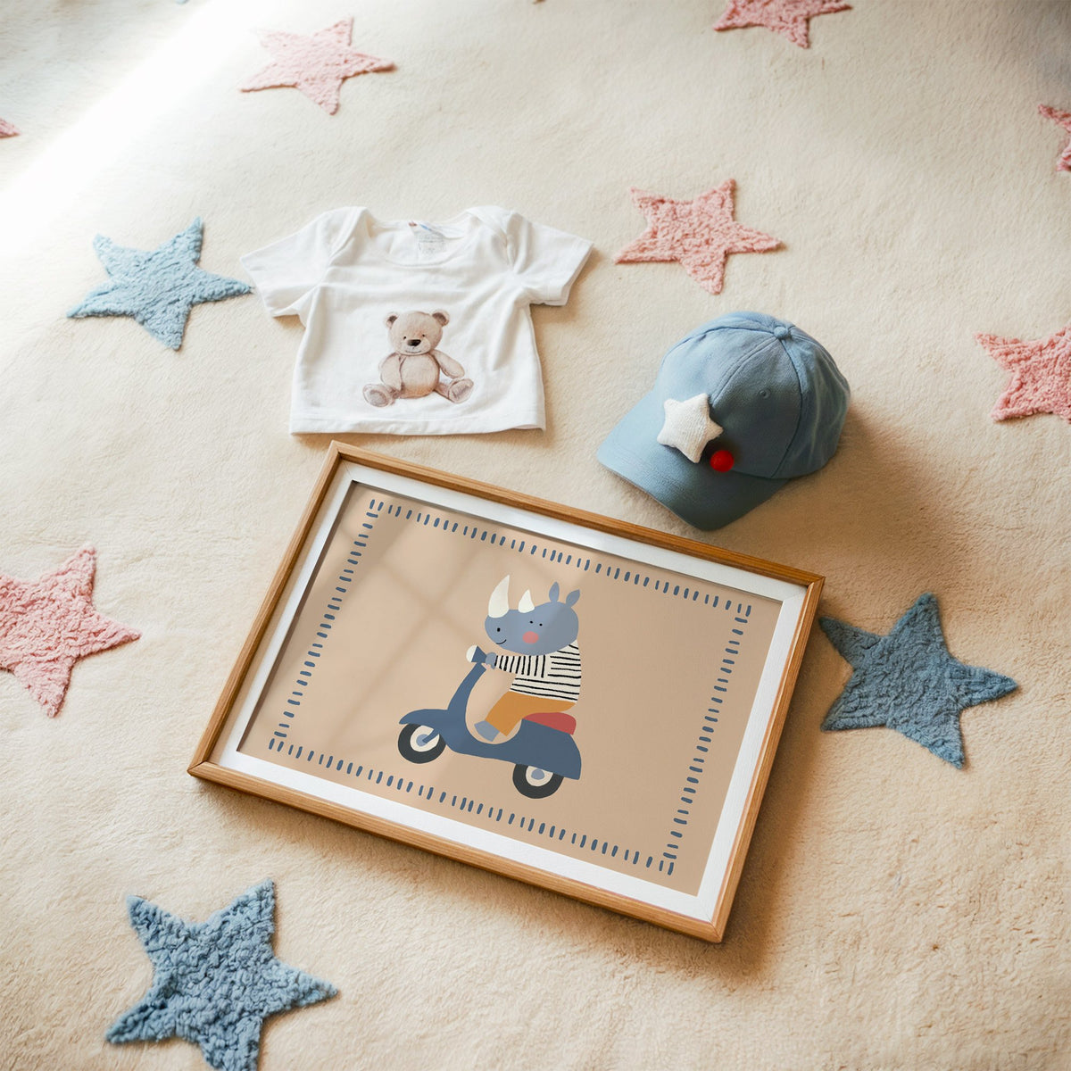 Landscape rhino on a blue scooter nursery print in a matted oak frame on a star rug with a baby tee
