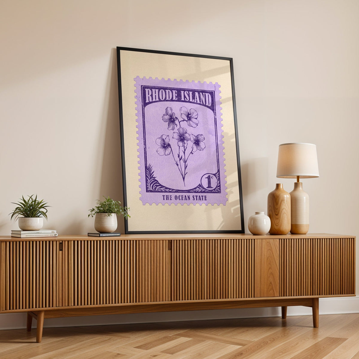 Rhode Island state flower print in a black frame leaning on a fluted wood credenza with vases and a lamp