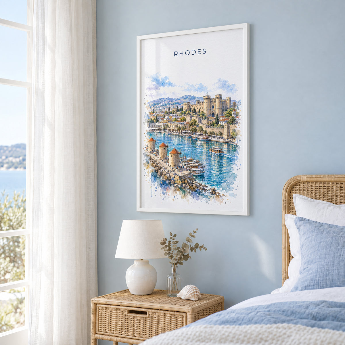 Rhodes watercolor print in a white frame on a pale blue wall beside a rattan bed in a coastal bedroom