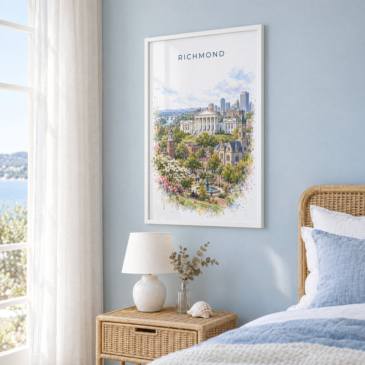 Richmond, Virginia watercolor print in a white frame on a pale blue wall beside a rattan bed in a coastal bedroom