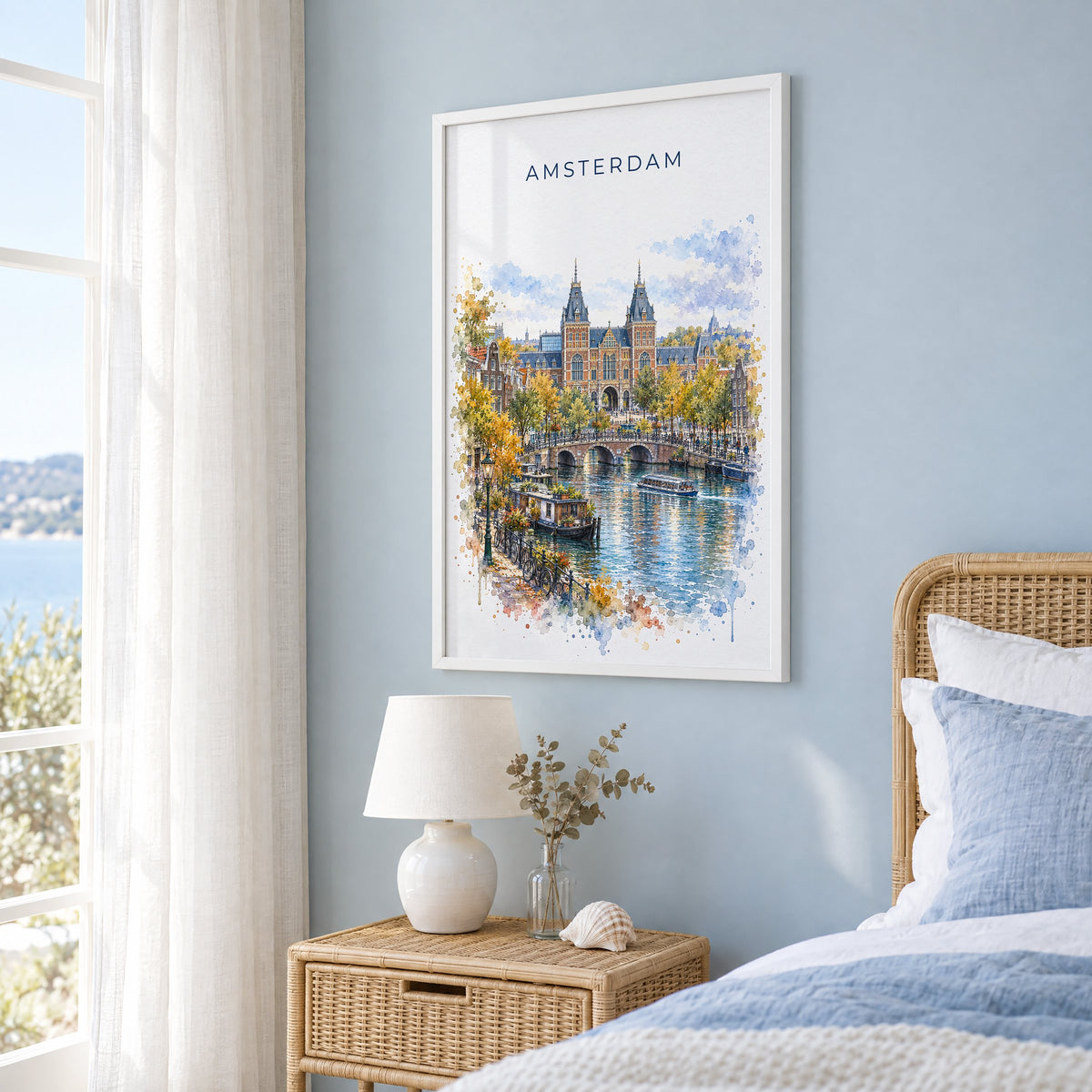 Rijksmuseum watercolor print in a white frame on a pale blue wall beside a rattan bed in a coastal bedroom