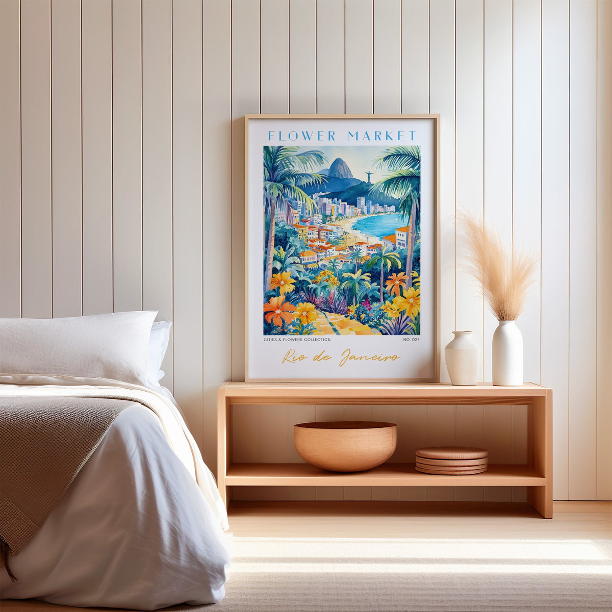 Rio de Janeiro flower market print in an oak frame on a wood bench against a white shiplap bedroom wall with pampas grass