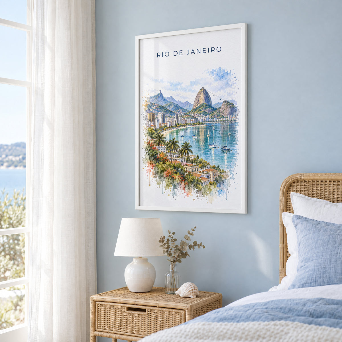 Rio de Janeiro watercolor print in a white frame on a pale blue wall beside a rattan bed in a coastal bedroom
