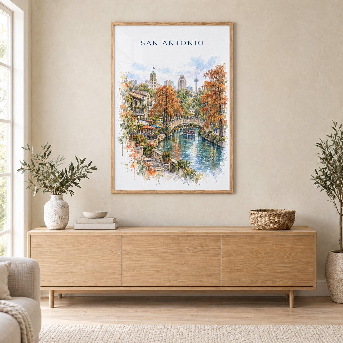 San Antonio River Walk watercolor print in an oak frame above a light wood sideboard in a Scandinavian living room