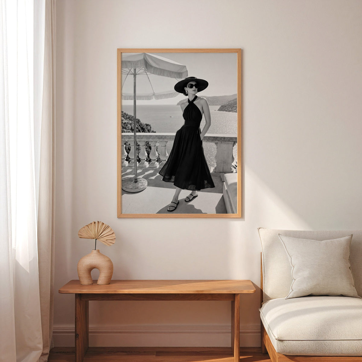 Black and white woman in halter dress on terrace print in an oak frame above a narrow console with an arched vase
