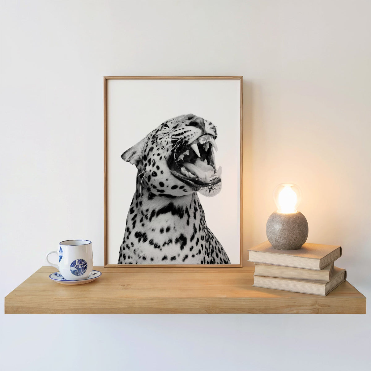 Roaring leopard portrait on white background print in an oak frame on a floating shelf beside a glowing lamp