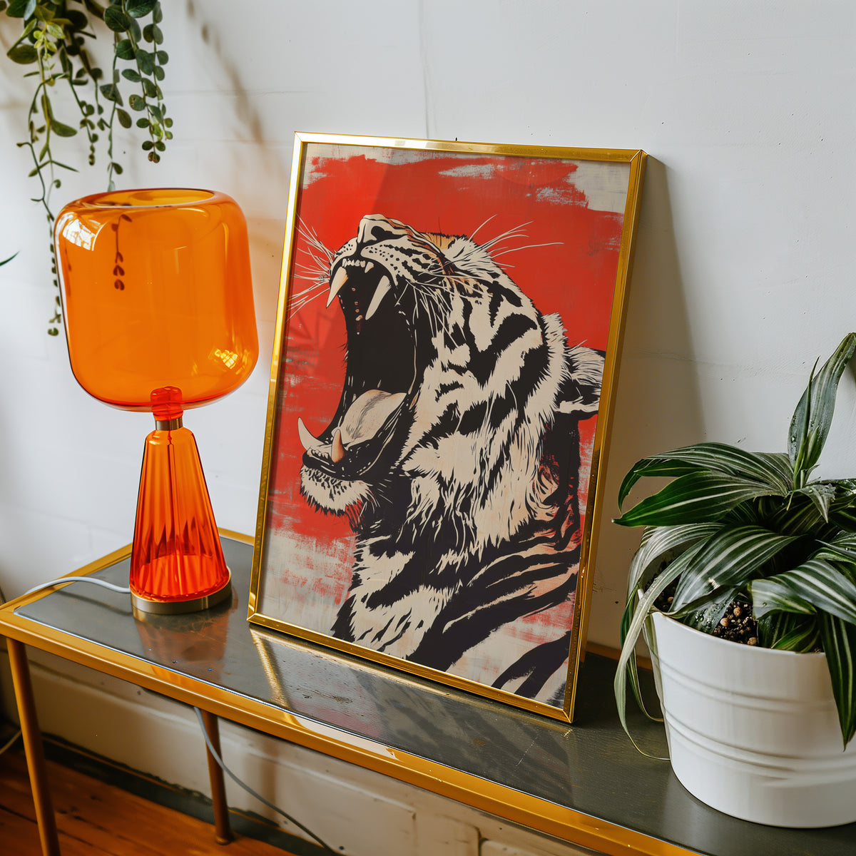 Roaring tiger head in profile print shown in a gold frame on a console beside an orange glass lamp
