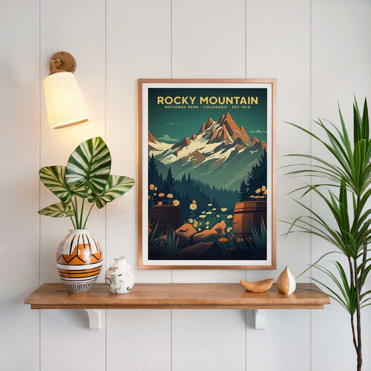 Rocky Mountain National Park print in a copper frame above an oak shelf on white shiplap with a sconce