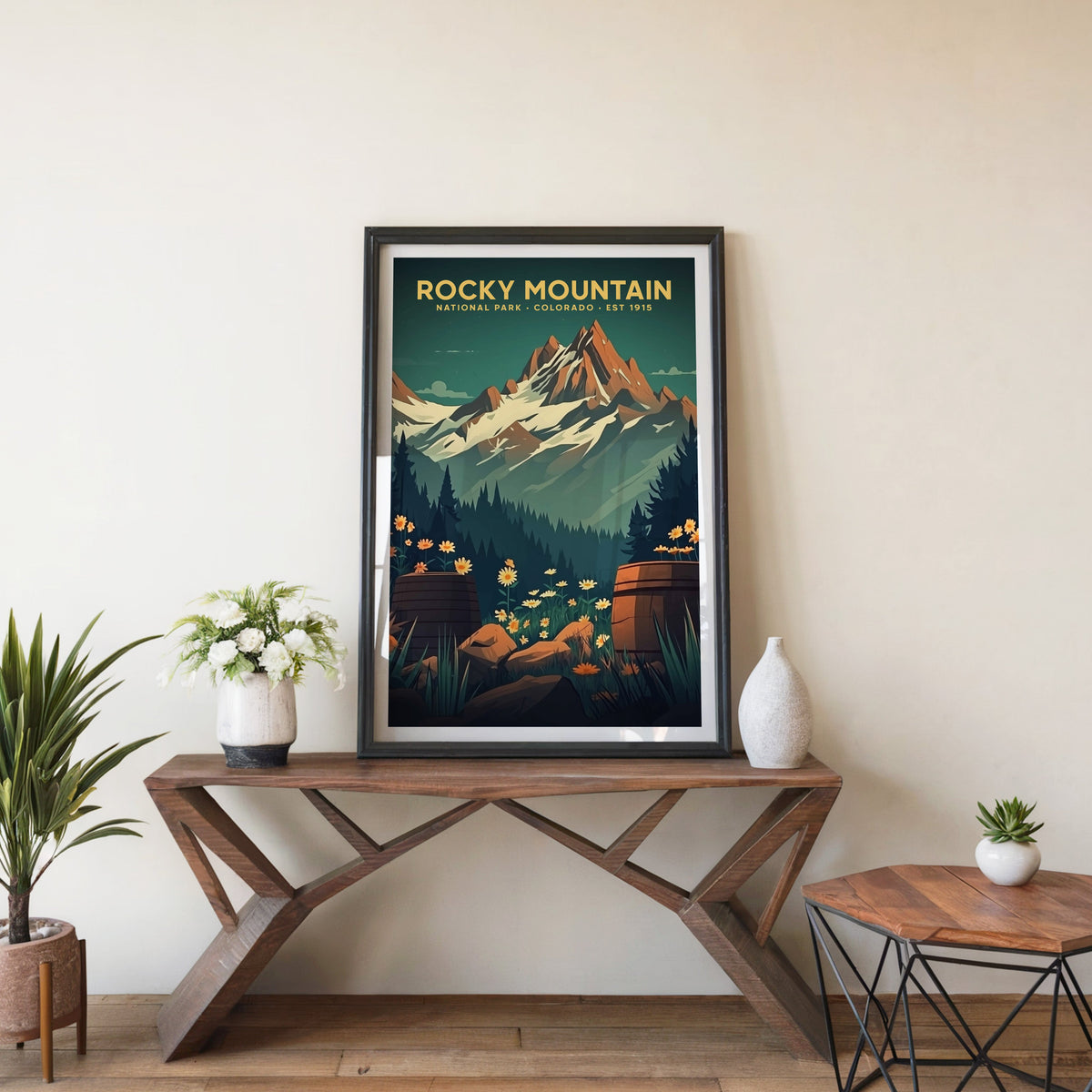 Rocky Mountain poster in a black frame on an entryway console table beside white flowers and a yucca