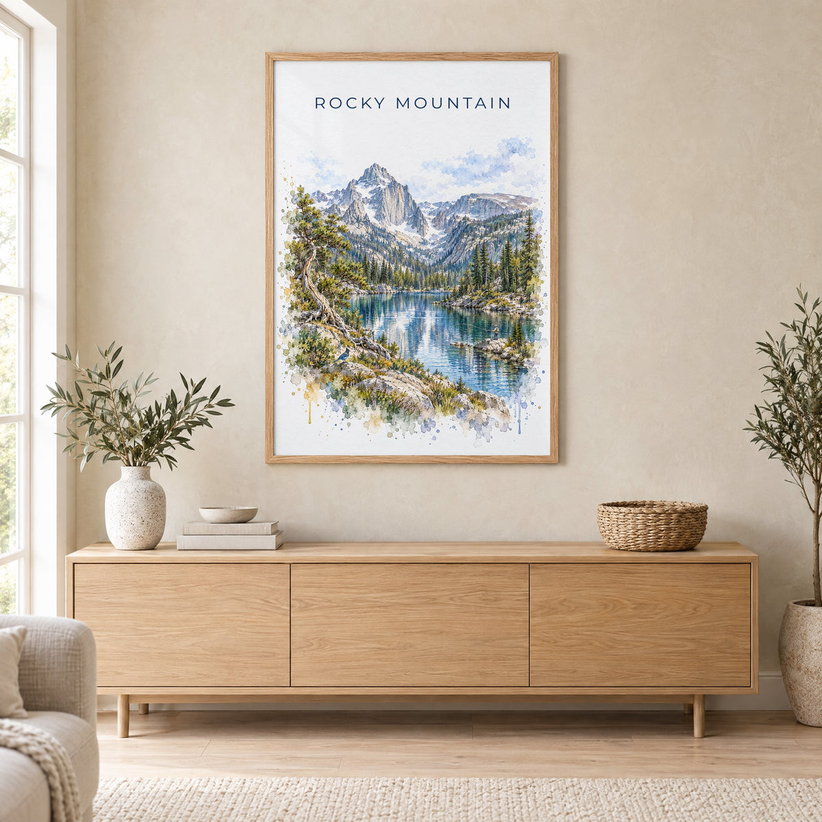 Rocky Mountain National Park watercolor print in an oak frame above a light wood sideboard in a Scandinavian living room