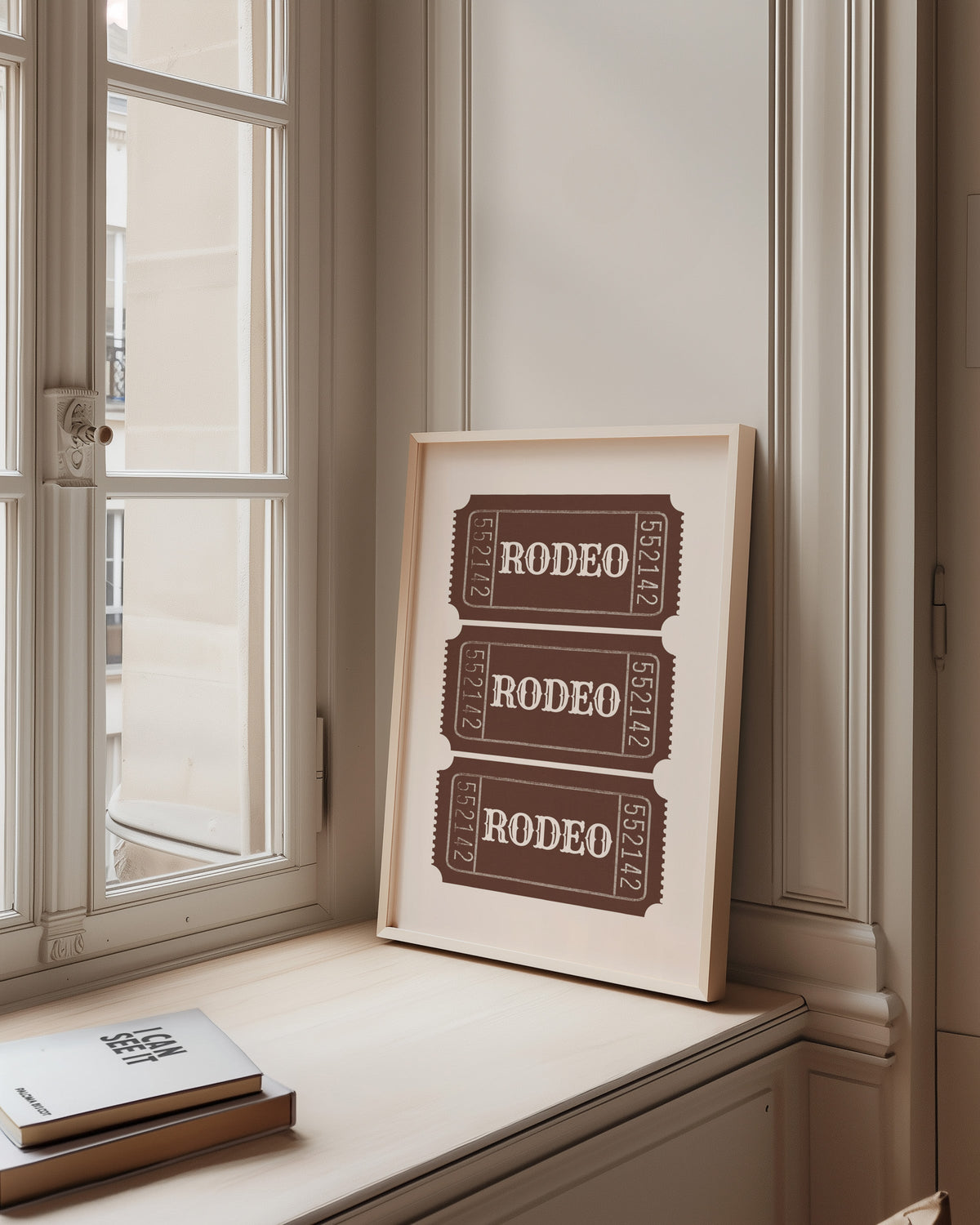 Rodeo ticket print in a pale wood frame on a sunlit window ledge