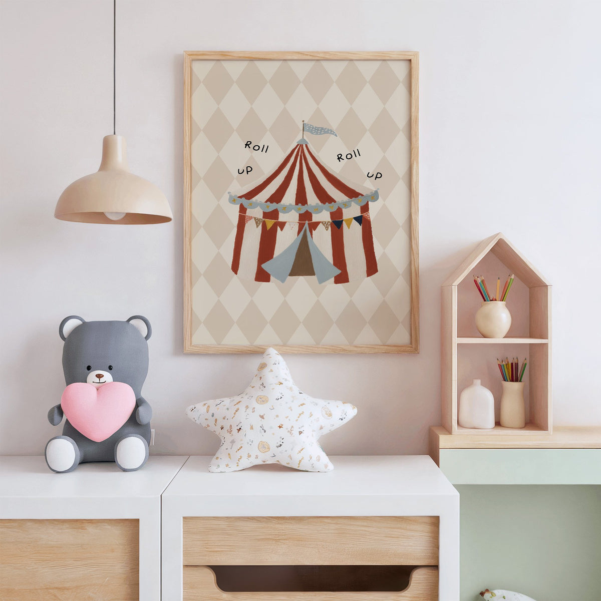 Roll up circus tent nursery print in an oak frame above a white dresser with a star pillow and house shelf