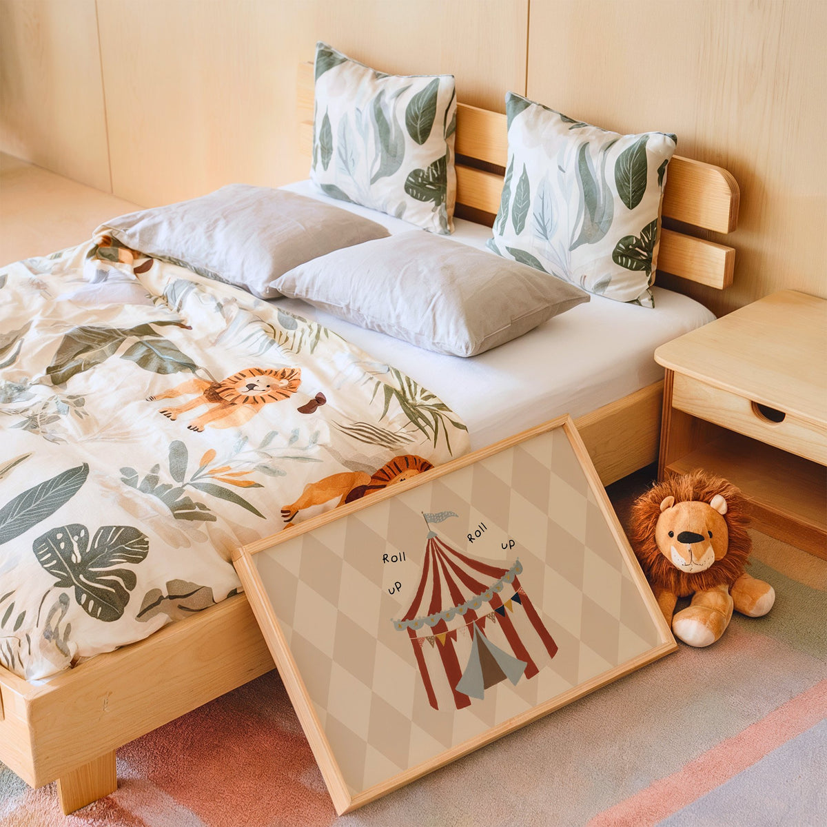 Landscape roll up circus tent nursery print in an oak frame leaning on a kids bed by a lion plush