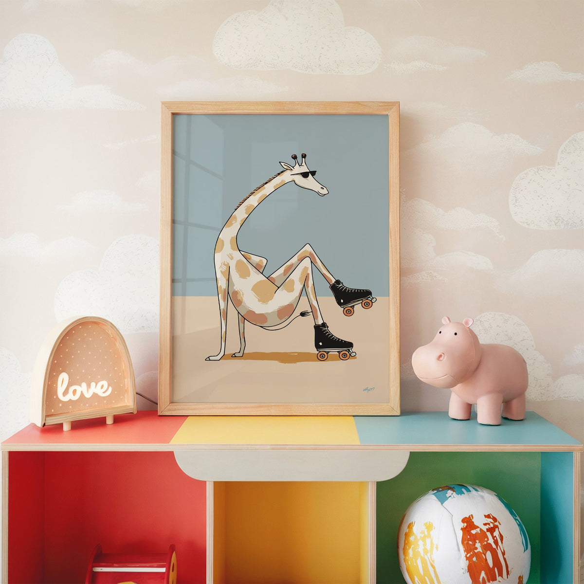Giraffe wearing roller skates nursery print in an oak frame on a rainbow toy shelf against cloud wallpaper