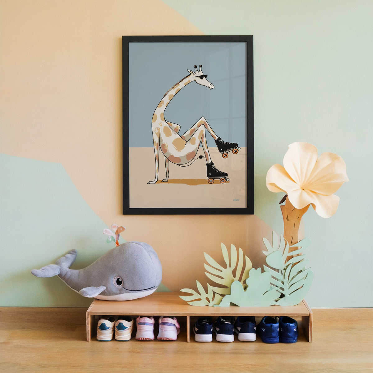 Giraffe wearing roller skates nursery print in a black frame on a mint and peach wall above a whale plush