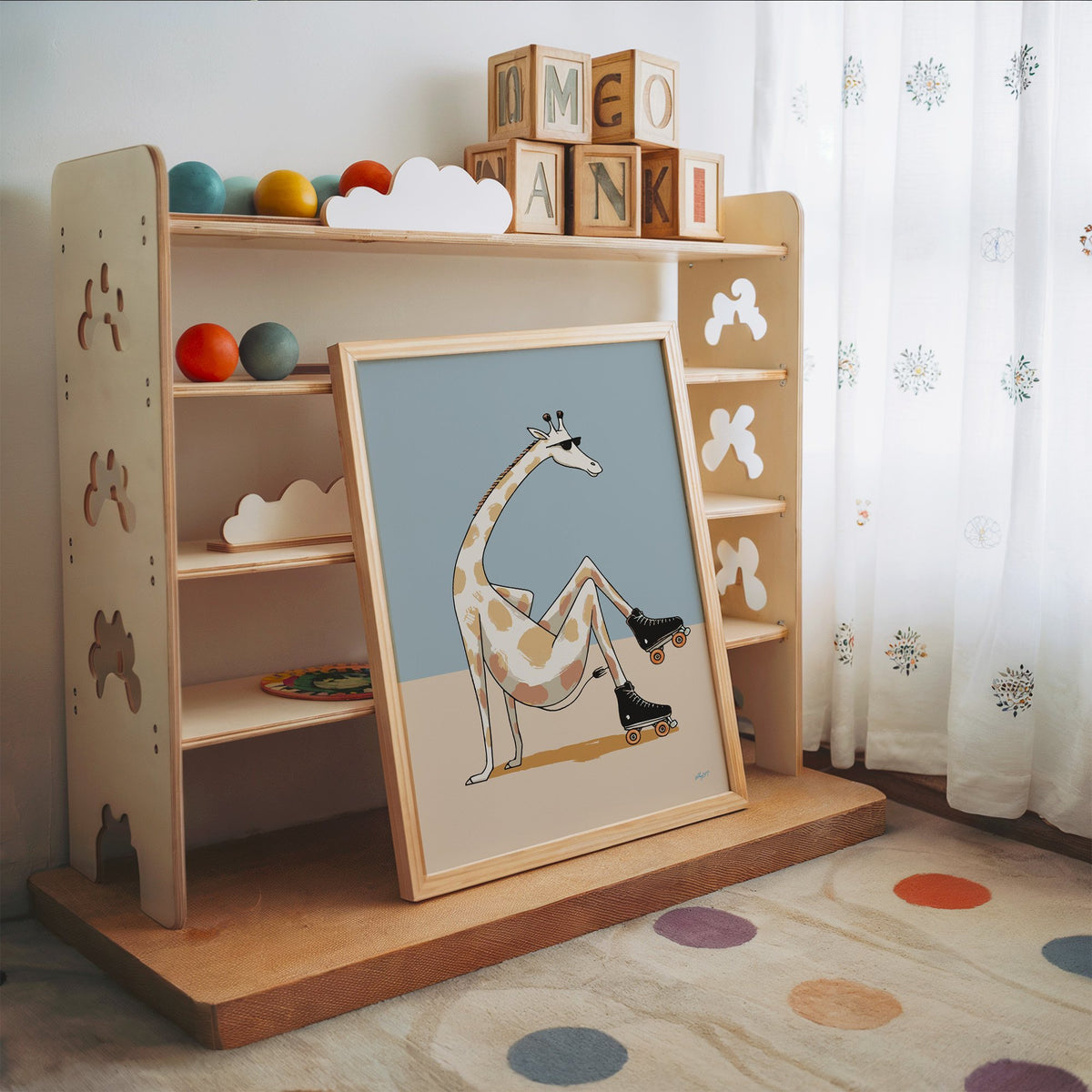 Giraffe wearing roller skates nursery print in an oak frame leaning on a toy shelf with wooden letter blocks