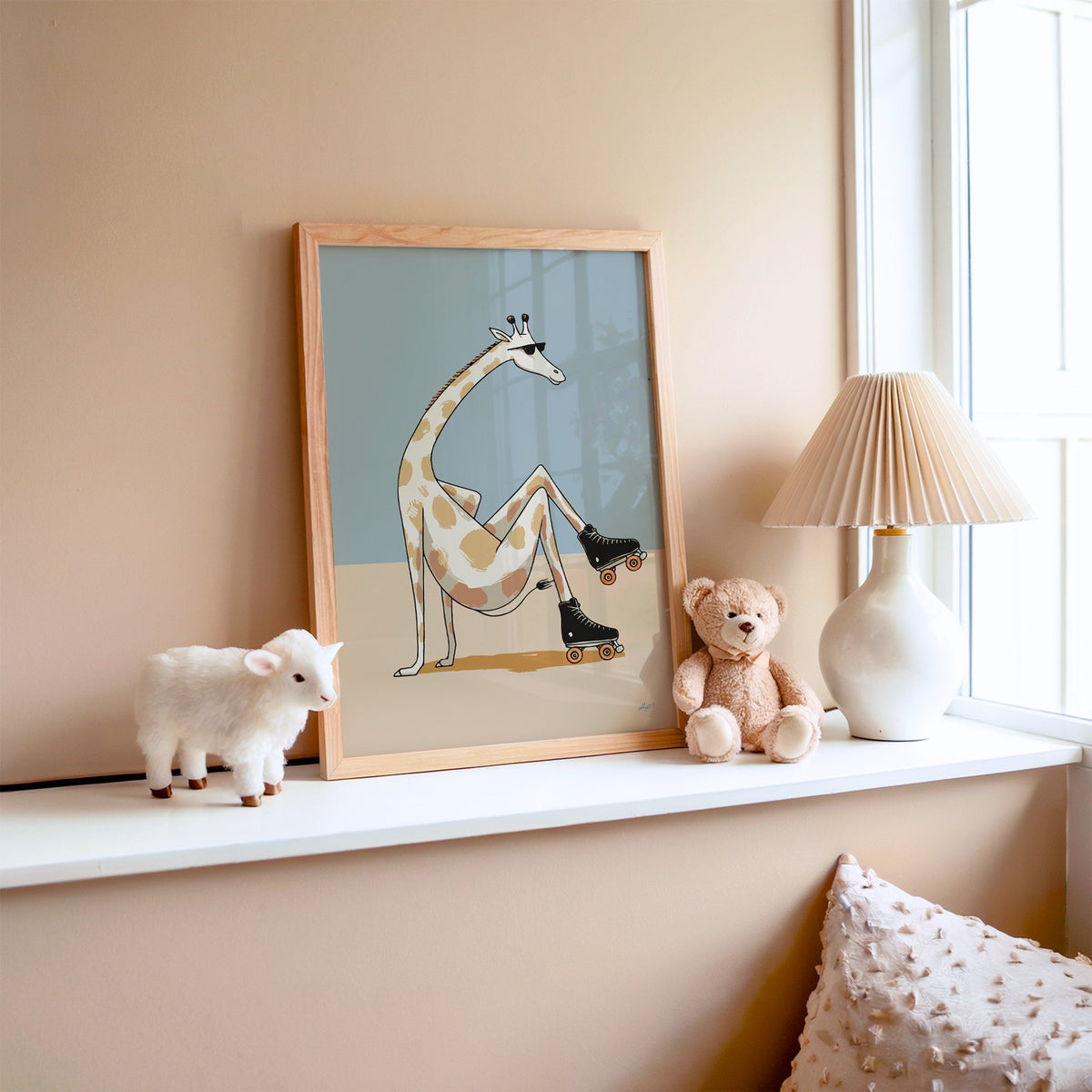 Giraffe wearing roller skates nursery print in an oak frame on a window ledge with a toy lamb and teddy