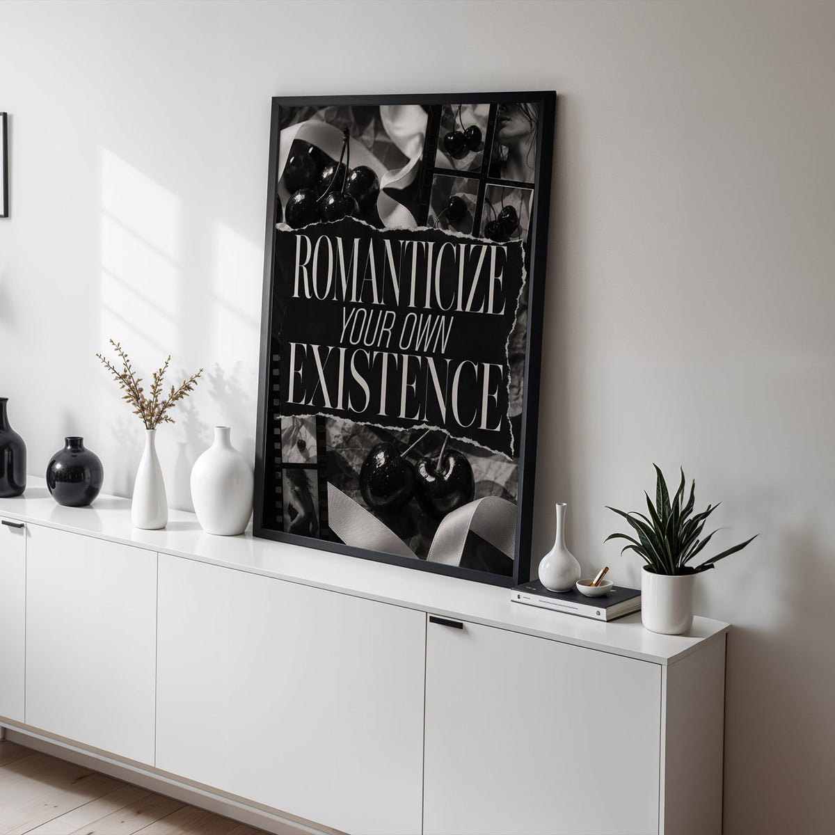 Romanticize your own existence cherry collage print in a black frame on a white sideboard with black and white vases