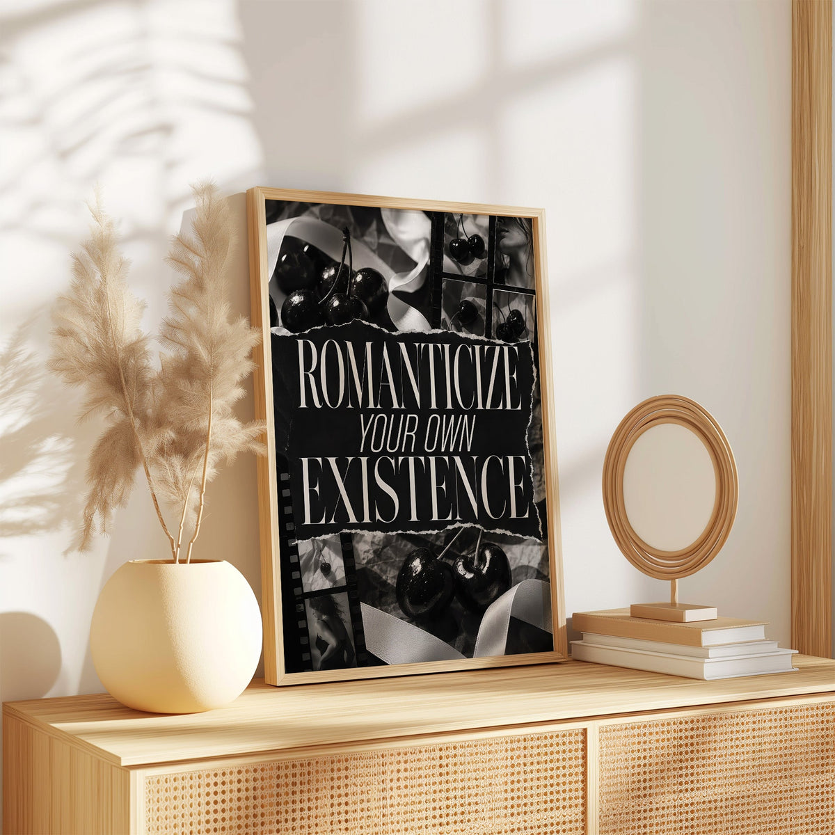 Romanticize your own existence cherry collage print in an oak frame on a rattan sideboard beside pampas grass
