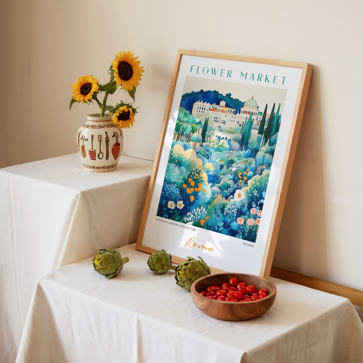 Rome flower market print in an oak frame leaning on a linen-draped table beside a vase of sunflowers
