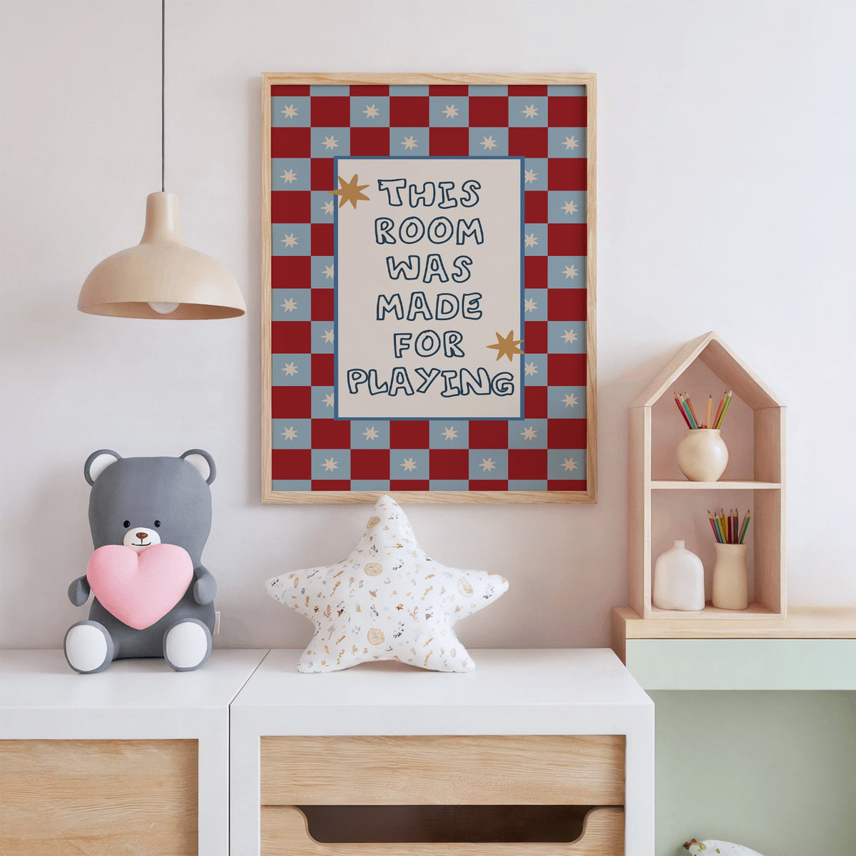 Room made for playing checkered nursery print in an oak frame above a white dresser with a star pillow and house shelf