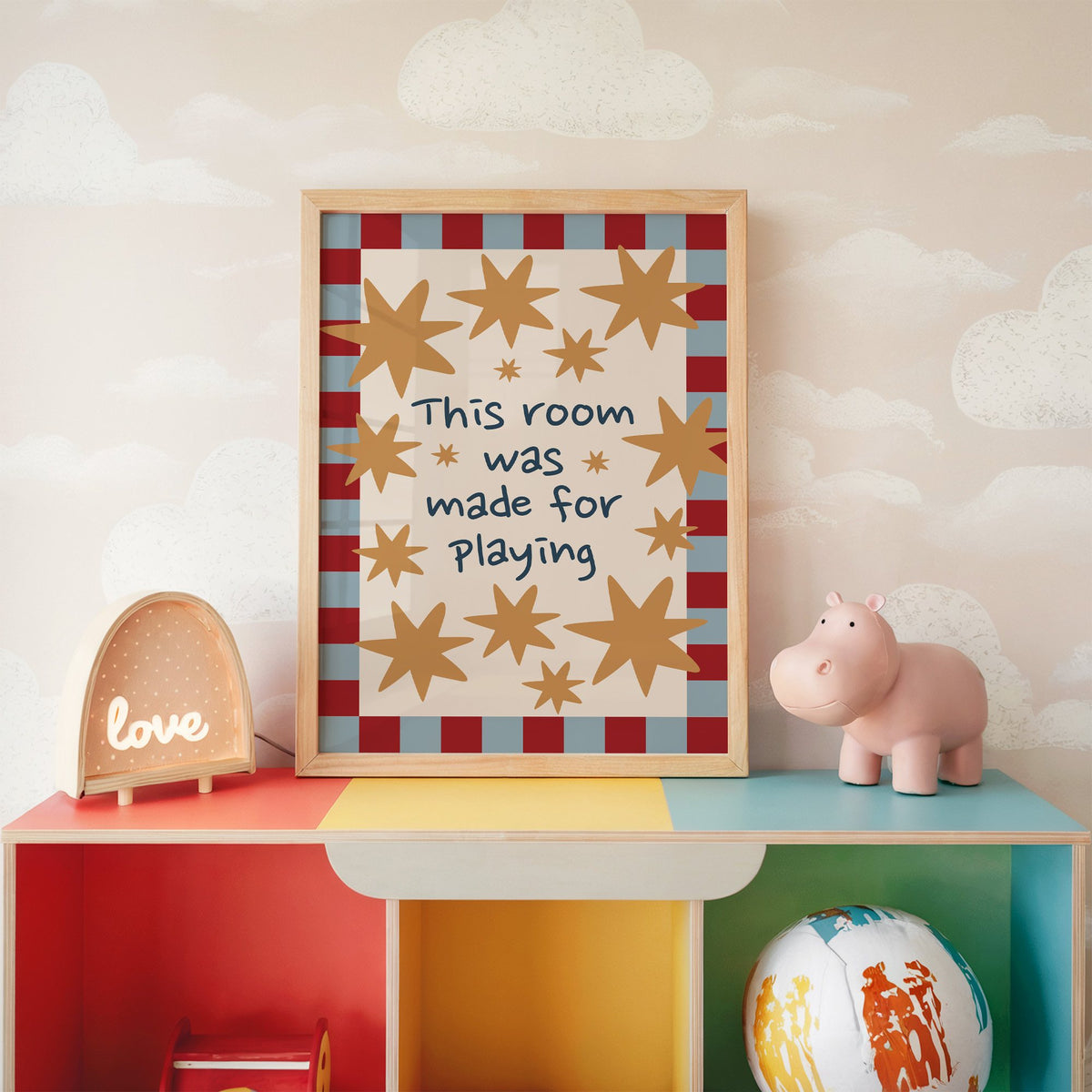 Room made for playing stars nursery print in an oak frame on a rainbow toy shelf against cloud wallpaper
