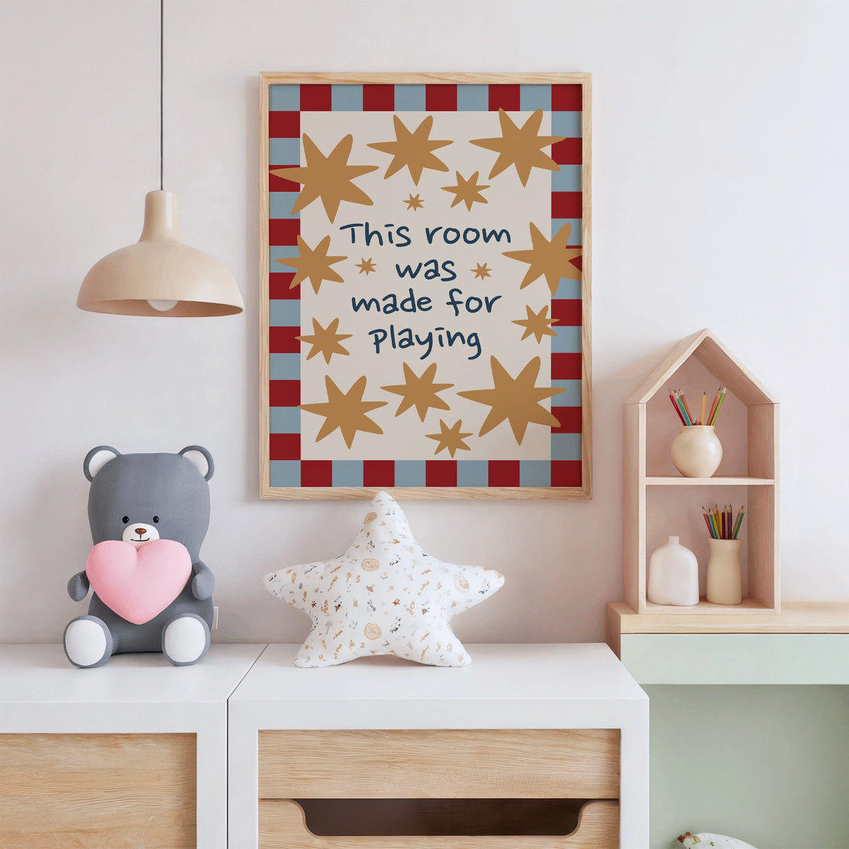 Room made for playing stars nursery print in an oak frame above a white dresser with a star pillow and house shelf