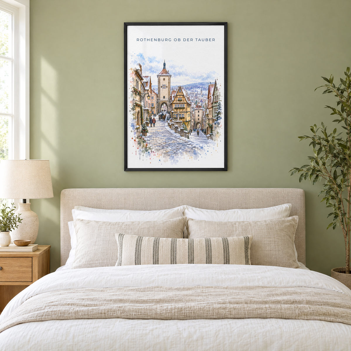 Rothenburg ob der Tauber watercolor print in a black frame above an upholstered headboard in a sage green bedroom