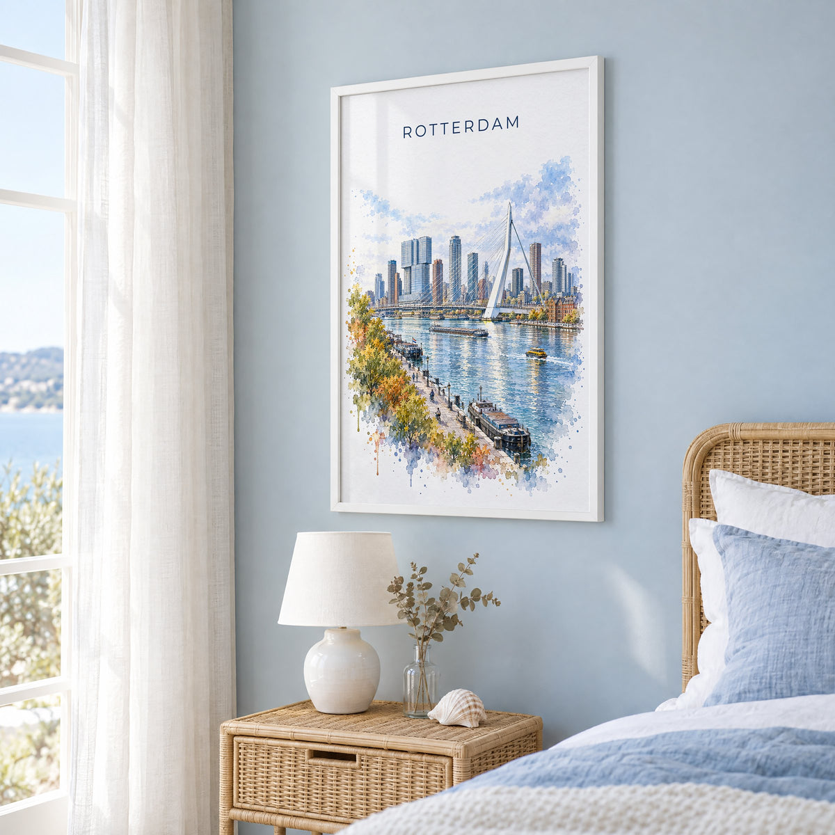 Rotterdam watercolor print in a white frame on a pale blue wall beside a rattan bed in a coastal bedroom