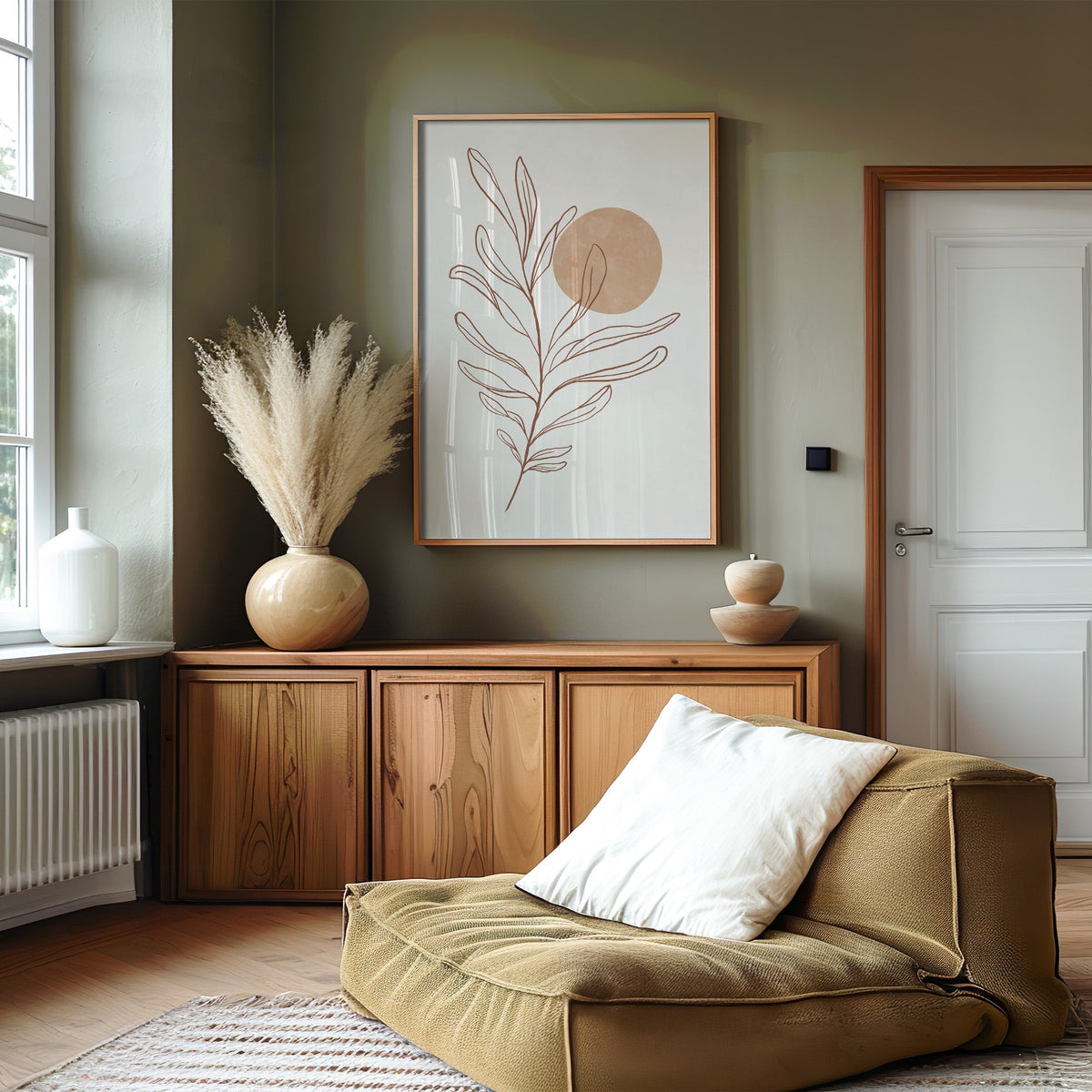 Rust line leaf branch and peach sun botanical print in an oak frame on an olive green wall above a wood sideboard with pampas