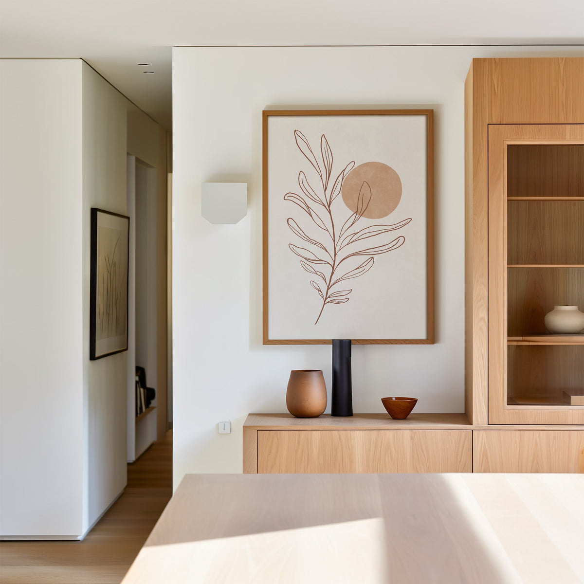 Rust line leaf branch and peach sun botanical print in an oak frame above a light oak sideboard in a dining room