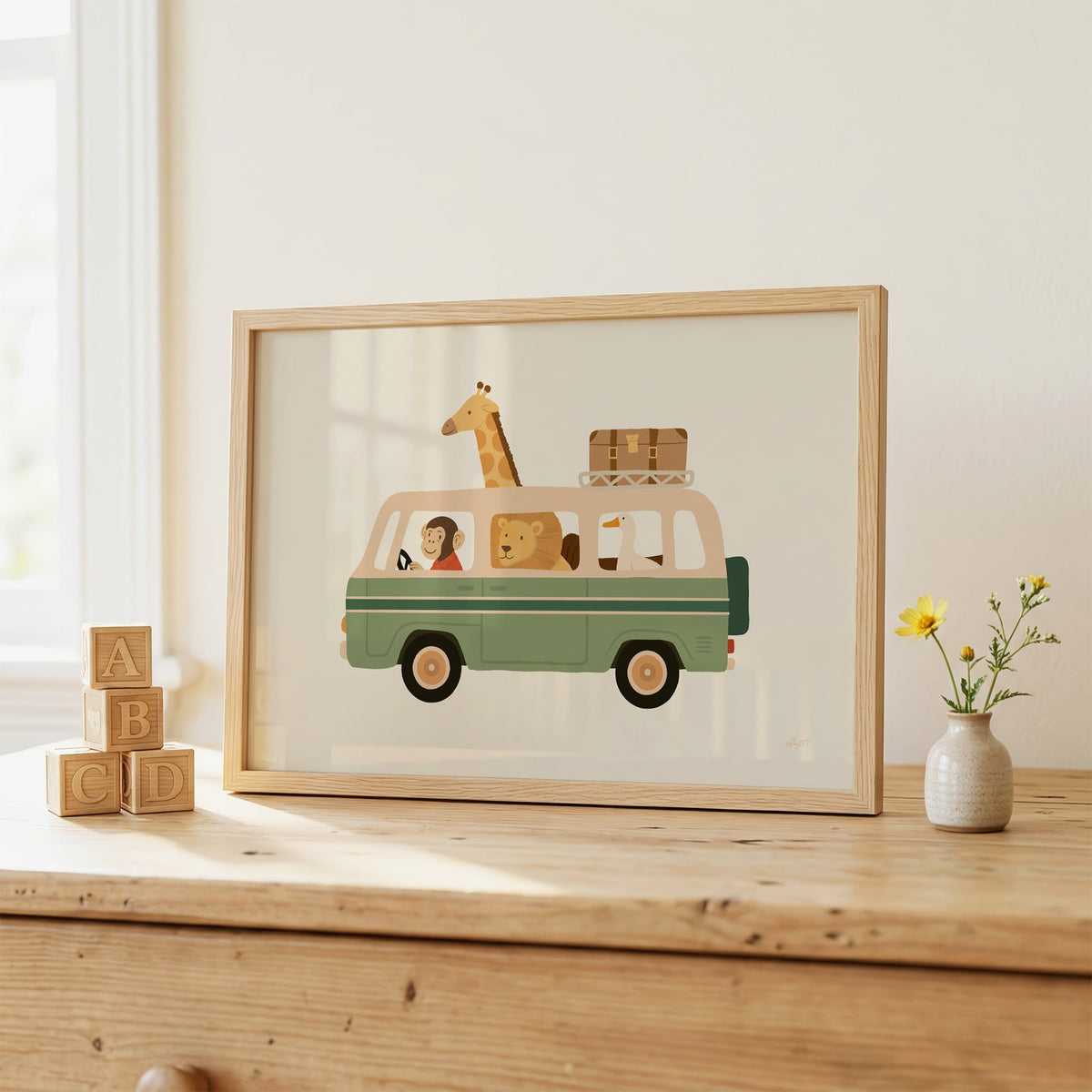 Safari animals riding green van nursery print in an oak frame on a wooden dresser beside ABC blocks