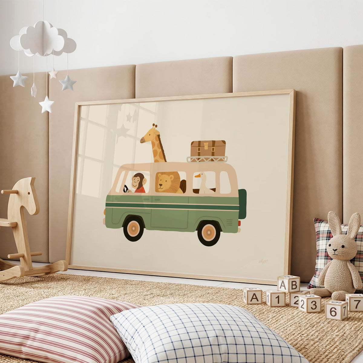 Safari animals riding green van nursery print in an oak frame on a padded wall by a wooden rocking horse