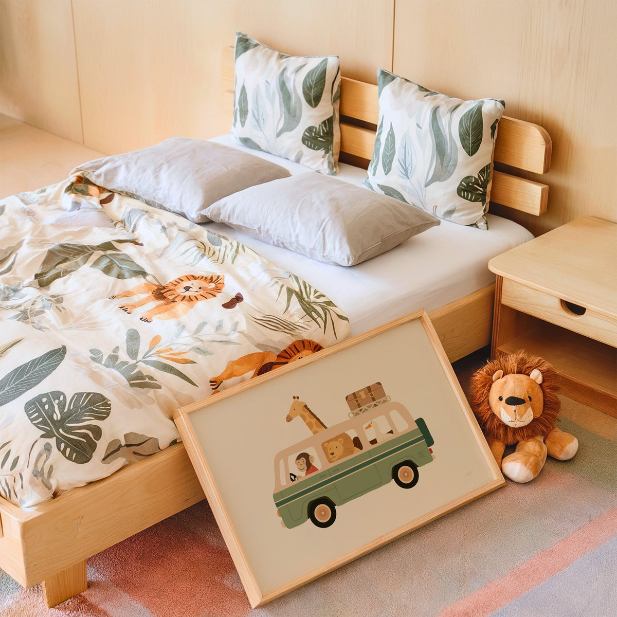 Safari animals riding green van nursery print in an oak frame leaning on a kids bed by a lion plush