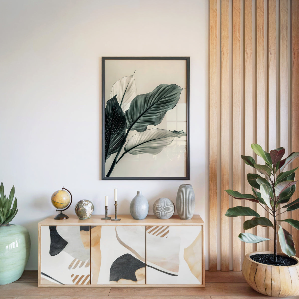 Sage green leaves abstract botanical print in a black frame above a light wood sideboard by a wood slat wall