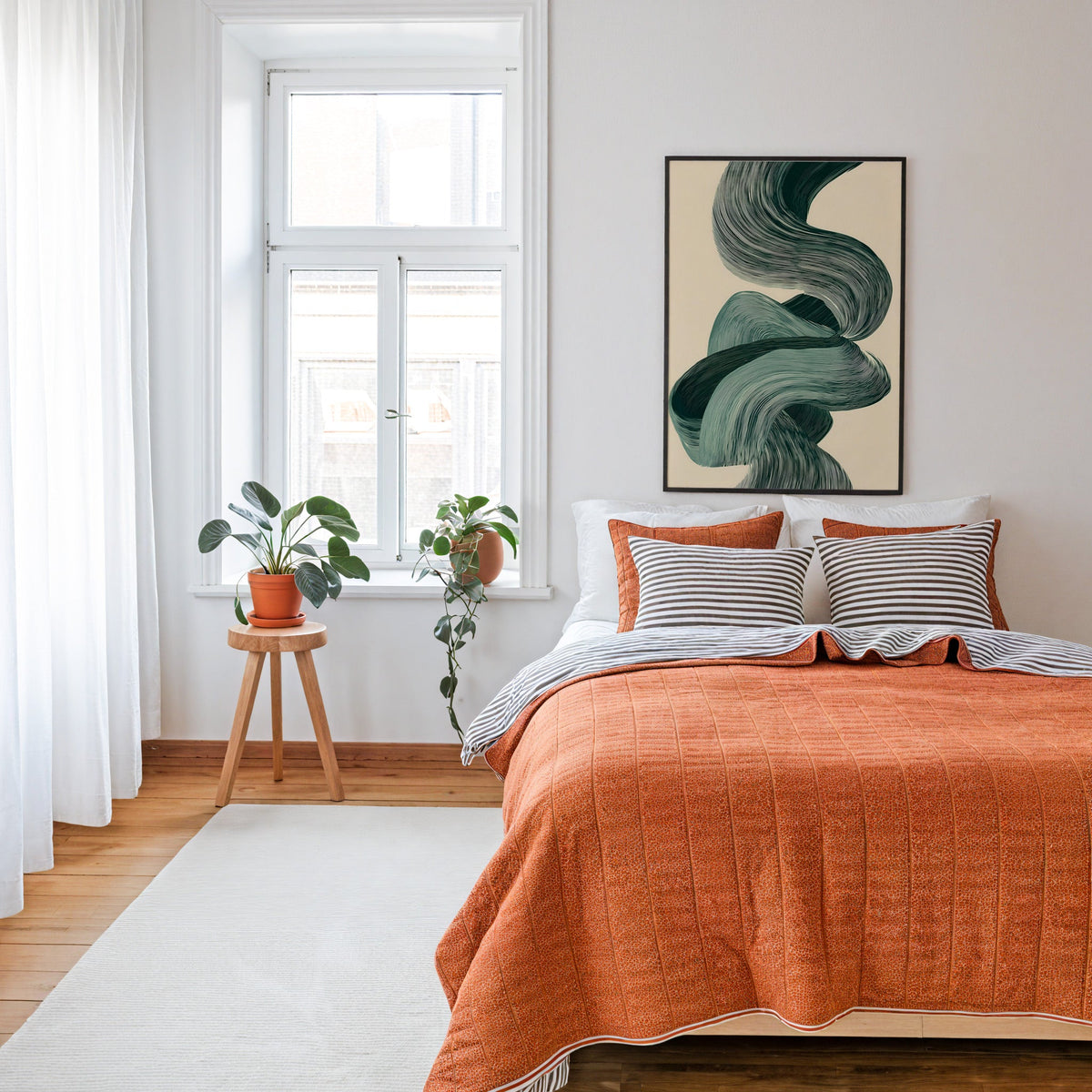 Sage green line ribbon swirl abstract print in a thin black frame above a bed with a rust orange quilt