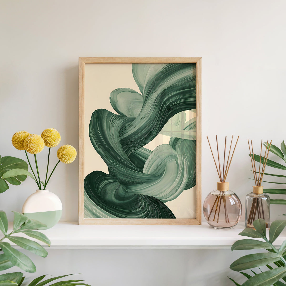 Sage green paint swirl abstract print in a light oak frame leaning on a white mantel with yellow flowers