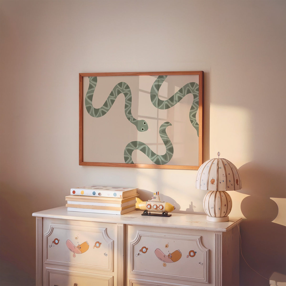 Landscape sage green snake nursery print in a cherry wood frame above a painted dresser and lamp