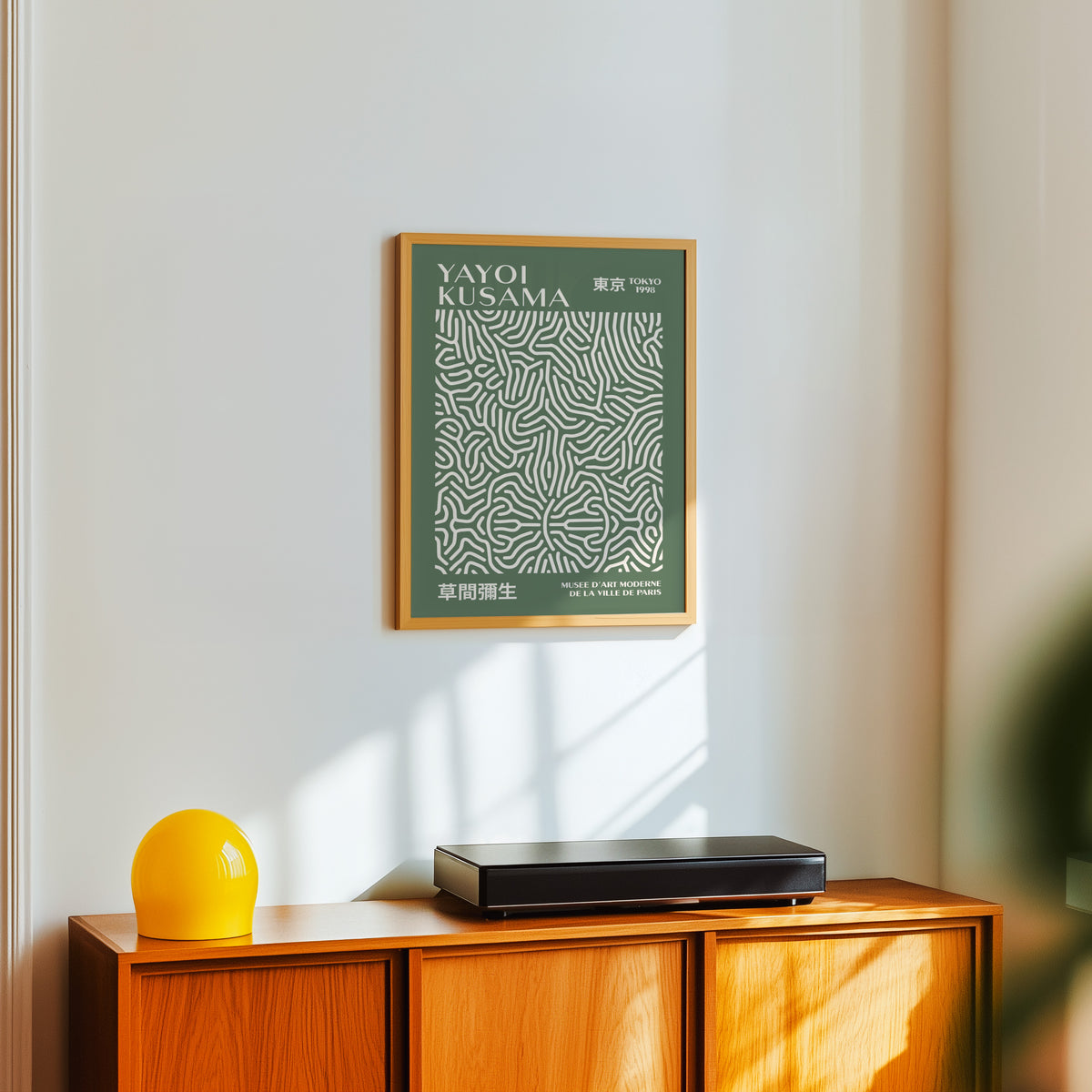 Yayoi Kusama inspired sage squiggle on deep green print above a sideboard with a yellow lamp
