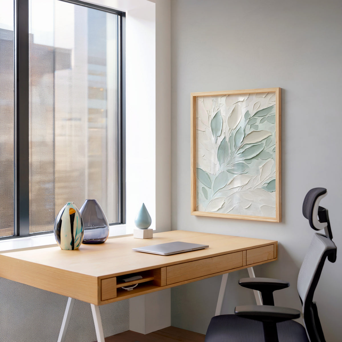 Sage and white impasto leaves botanical print in a pale wood frame above a home office desk by a tall window