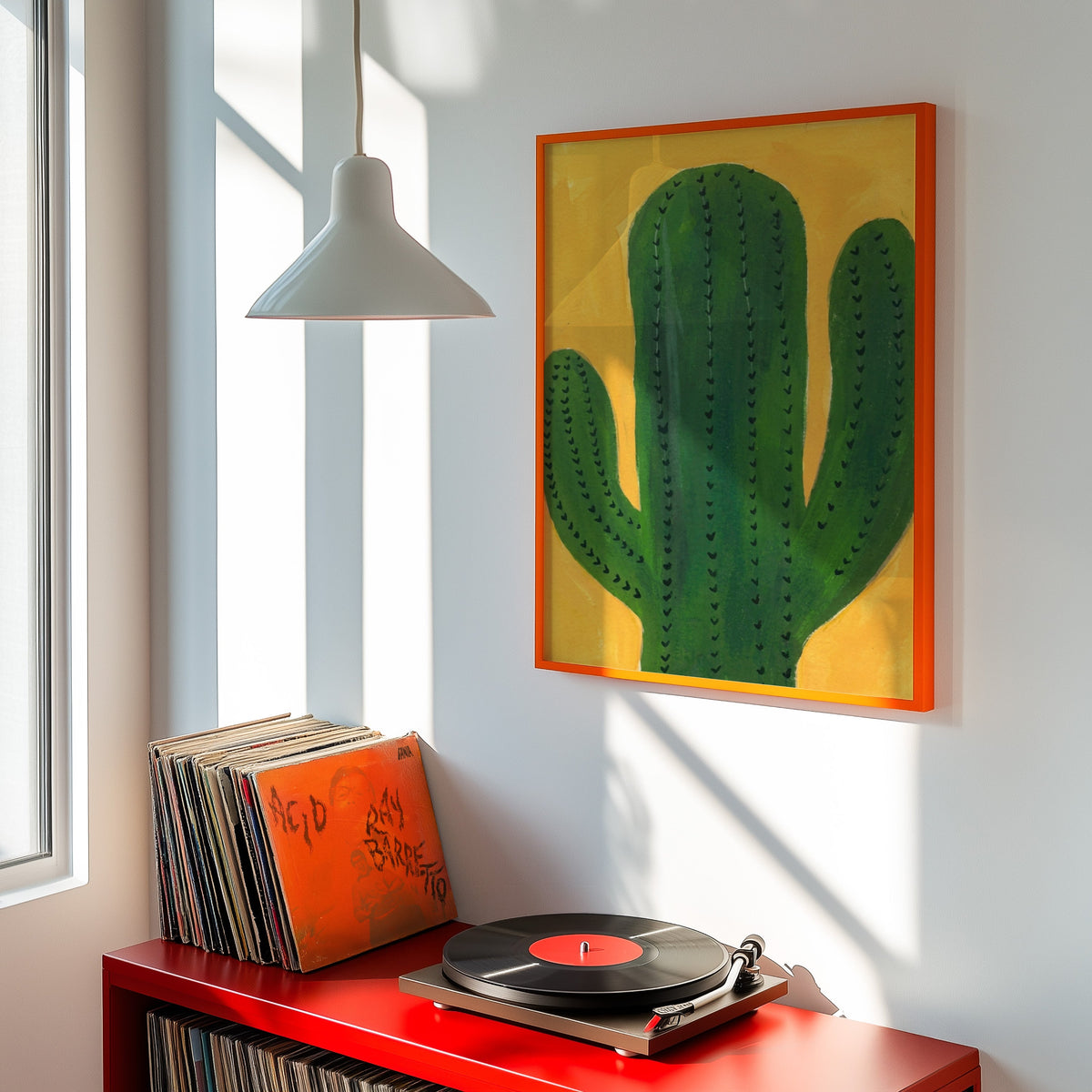 Three-armed cactus print shown in an orange frame above a red record cabinet and turntable