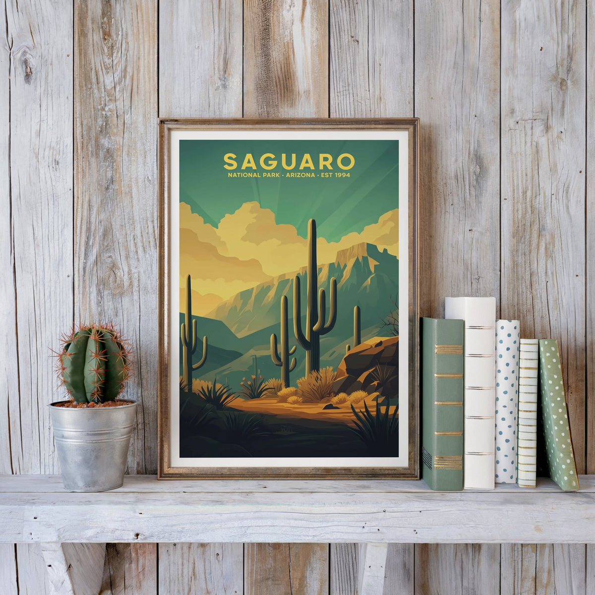 Saguaro poster in an antique gold frame against whitewashed farmhouse planks beside books and a cactus