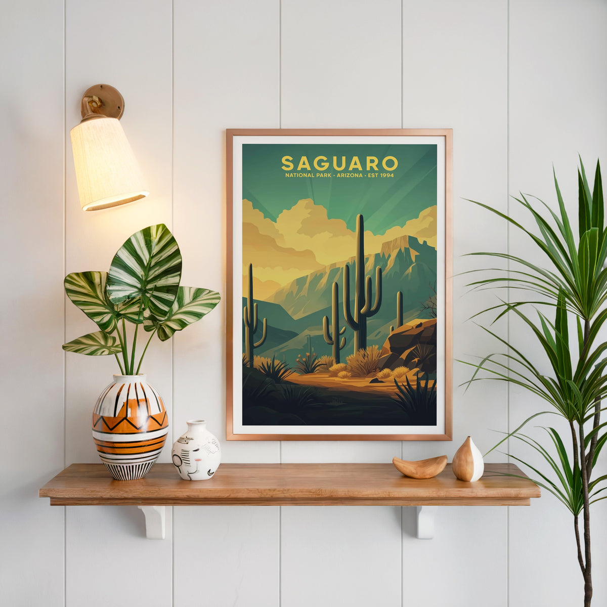Saguaro National Park print in a copper frame above an oak shelf on white shiplap with a brass sconce