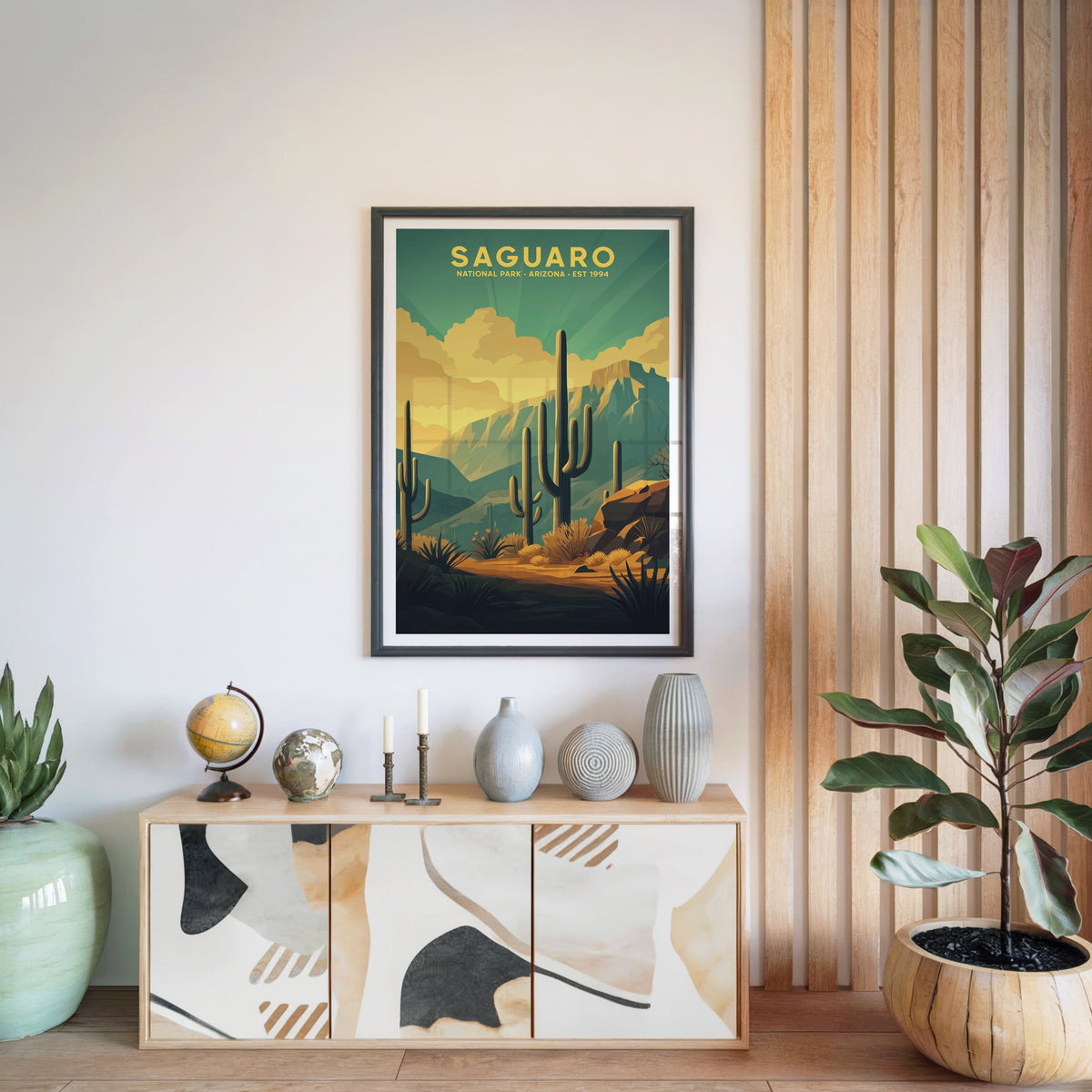 Saguaro National Park print in a black frame above a light wood sideboard with a globe and ceramic vases