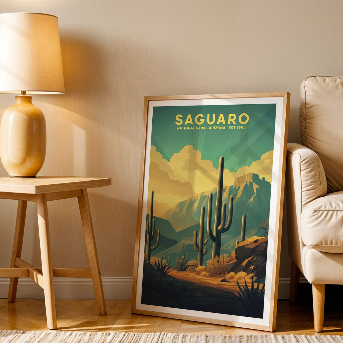 Saguaro print in an oak frame beside a cream armchair and an amber lamp in warm afternoon light