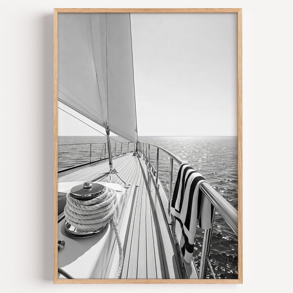 Sailboat deck with rope coil and striped towel print in a light oak frame on a plain white wall